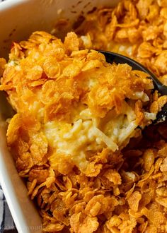 a casserole dish with cheese and potato chips in it is being spooned into the casserole