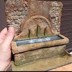 a hand is holding up a fountain in front of a building