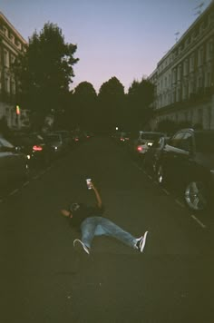 a person laying on the ground with their arms in the air while holding a drink