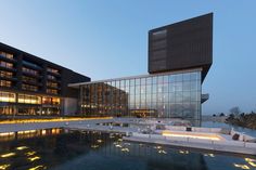 the building is lit up at night and reflecting in the water