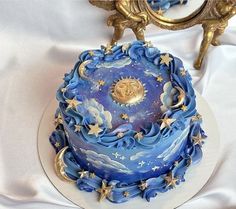 a blue and white cake with gold stars on it sitting on a table next to a mirror