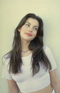 a woman with long black hair wearing a white shirt