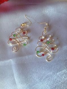 a pair of earrings sitting on top of a white cloth next to a red rose