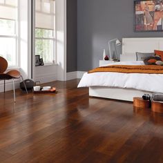 a bed sitting on top of a wooden floor in a bedroom