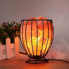 a lamp that is sitting on a table next to some potted plants and flowers