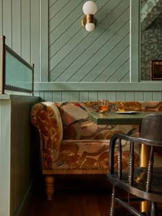 a couch and chair in a room with wood floors, green walls and wooden flooring