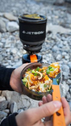 a person holding a bowl with food in it and a camera behind them on the ground