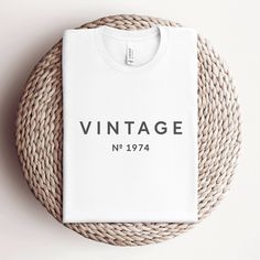 a white t - shirt with the words vintage on it next to a wicker basket