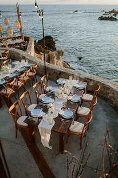 an outdoor dining area overlooking the ocean with tables and chairs set up for formal dinner