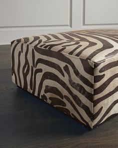 a zebra print footstool sitting on top of a hard wood floor next to a white wall