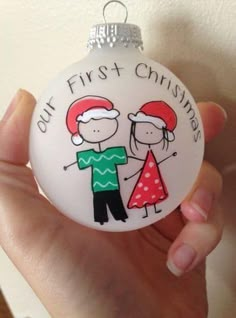 a hand holding a white ornament with a drawing of two people on it