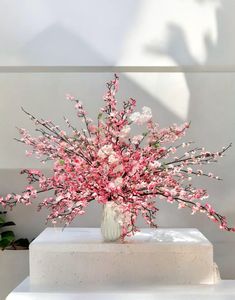 a vase filled with pink flowers sitting on top of a white pedestal