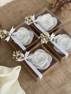 four small boxes with white roses in them