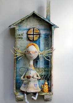 an altered doll is sitting in front of a house shaped like a woman holding a cup