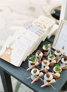 a table topped with potted plants next to an open book and small books on top of each other