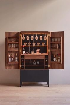 an old fashioned liquor cabinet with many bottles and glasses on it's doors, in front of a white wall