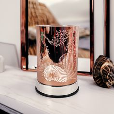 a pink candle holder sitting on top of a white mantle next to a sea shell