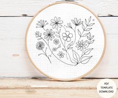 a embroidery pattern with flowers and leaves in black ink on a white wooden background, ready to be embroidered onto