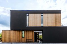 two people sitting at a table in front of a black and wood building with large windows