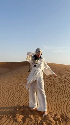 a man in white clothes standing on top of a desert