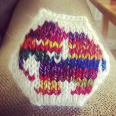 a colorful knitted object sitting on top of a couch next to a wooden table