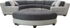 a grey and white sectional couch sitting on top of a wooden table next to a round ottoman