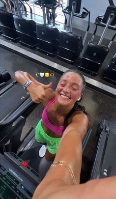 a woman is smiling as she rides on an exercise machine at the gym with her arm outstretched