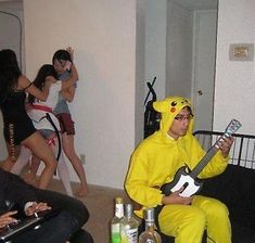 a man in a pikachu costume plays the guitar while others dance around him