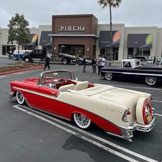 an old red and white convertible car parked in front of a pirch auto show