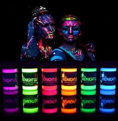 two people standing next to each other with neon paint on their faces and hands in front of them