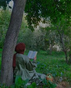 a woman sitting under a tree reading a book