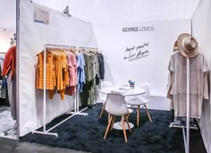 a clothing store display with clothes hanging on racks and chairs in front of the rack