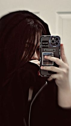 a woman taking a selfie in front of a mirror with her cell phone up to her face