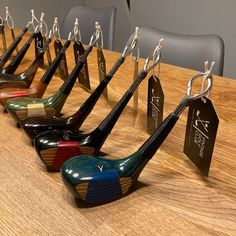 several pairs of golf clubs with tags attached to them sitting on a table in front of chairs