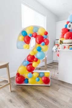 the number two is made out of balloons and sits in front of a table with chairs