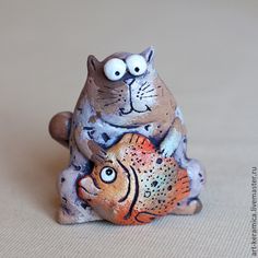 a ceramic cat and fish figurine sitting next to each other