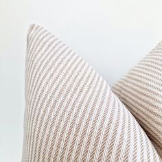 a close up view of a beige and white striped pillow on a white background with the corner of the pillow facing upwards