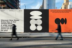 two people walking down the street in front of large billboards with different designs on them