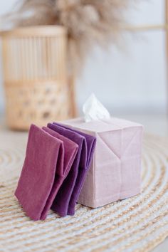 three folded napkins sitting on top of a table next to a basket and plant