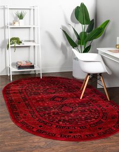 a large red rug in the corner of a room with a chair and potted plant