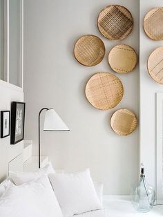 a bedroom with white bedding and wicker baskets hanging on the wall above it