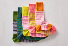 five pairs of colorful socks sitting next to each other on a white surface, with one sock folded up in the middle