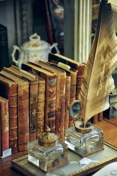 an old book set on a table with a feather quill and other books in front of it