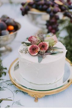 there is a cake with fruit on it and other food items around the cake table