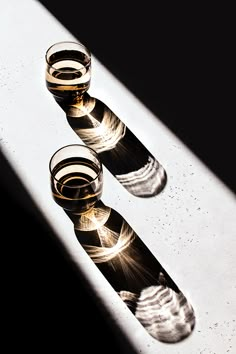 three shot glasses sitting on top of a counter next to each other in the sunlight