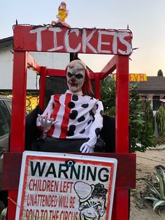 a clown sitting on top of a red chair next to a sign that says tickets