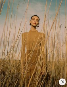 a woman standing in the middle of tall grass