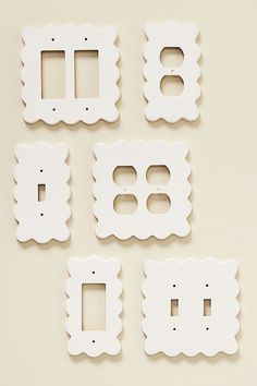 four white switchplates and two outlet covers on a beige surface with one facing the camera