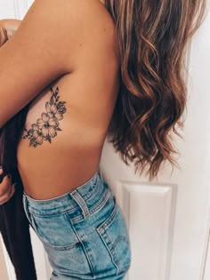 the back of a woman's shoulder with flowers tattooed on her left arm and chest