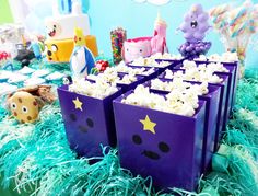 there are many purple boxes that have popcorn in them on the table with other decorations